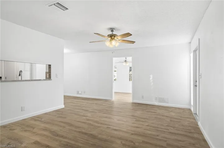 Unfurnished living room featuring ceiling fan, LVP wood-style floors, and a textured ceiling