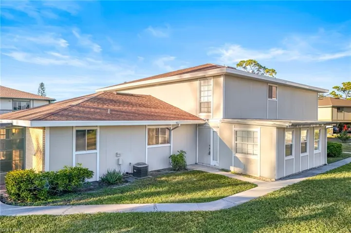 Rear view of the building featuring a lawn and central AC