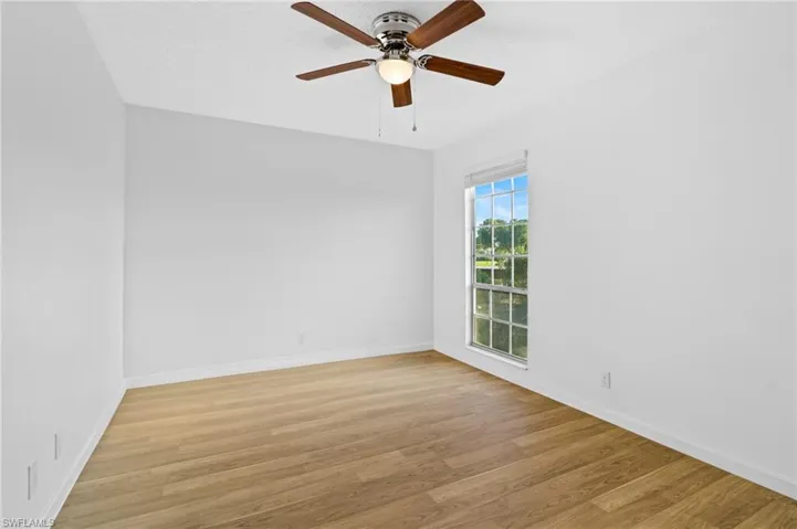 Empty room with a textured ceiling, light wood-type flooring, and ceiling fan