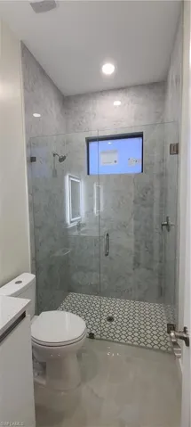 Bathroom with vanity, a shower with door, and toilet