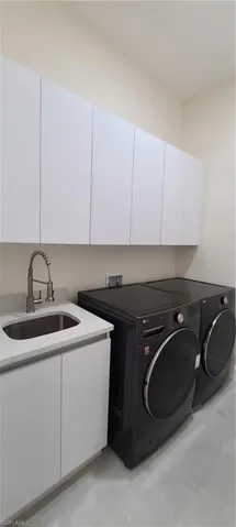 Laundry room featuring sink, separate washer and dryer, and cabinets