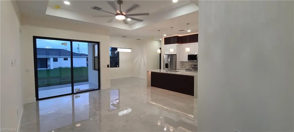 Kitchen featuring appliances with stainless steel finishes, ceiling fan, decorative backsplash, pendant lighting, and a raised ceiling