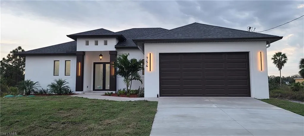 View of front of property featuring a front lawn and a garage