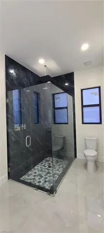 Bathroom featuring toilet and a shower with door