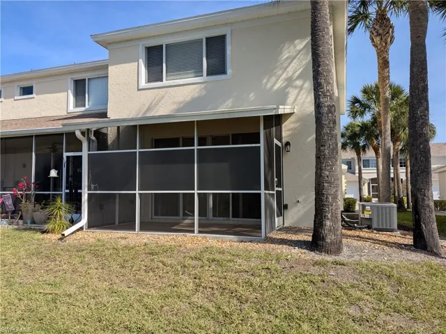 Rear view of property featuring stucco siding, a lawn, and a sunroom