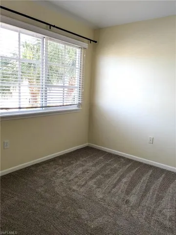 Spare room with dark carpet and baseboards