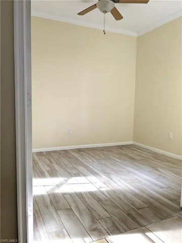 Spare room with wood tiled floors, crown molding, and a ceiling fan