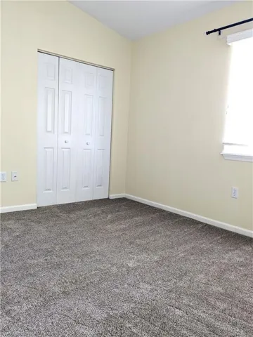 Unfurnished bedroom featuring dark colored carpet and a closet
