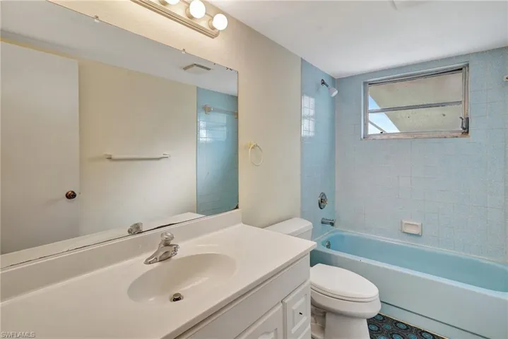 Full bathroom with vanity, tiled shower / bath, and toilet