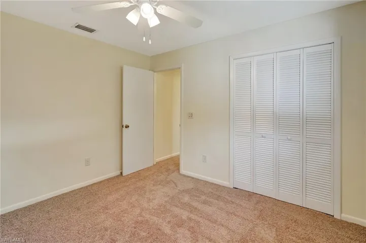 Unfurnished bedroom with ceiling fan, light colored carpet, and a closet