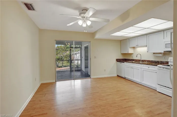 Kitchen featuring light wood-type flooring, white appliances, ceiling fan, and sink