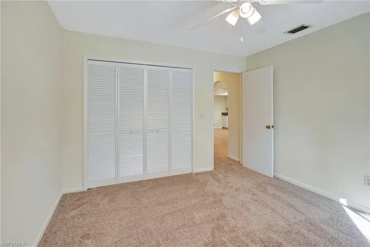 Unfurnished bedroom featuring ceiling fan, light carpet, and a closet