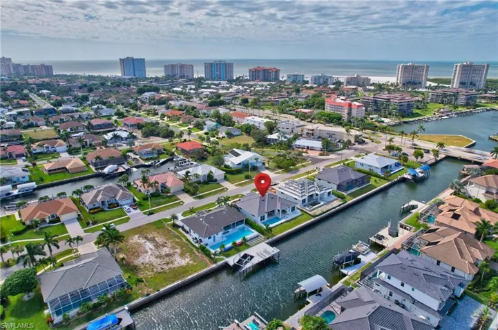 Waterfront property with private dock, featuring a private pool and canal access, with multiple high-rise buildings and the ocean visible in the distance