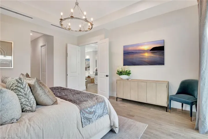 Spacious room featuring wood-finish flooring, a contemporary chandelier, recessed lighting, and double doors