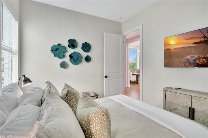 Bedroom featuring light-toned walls and wood-finish flooring visible through the doorway