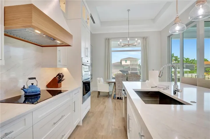 Contemporary kitchen featuring white cabinetry, light countertops, wood-finish flooring, a built-in oven, and a large window