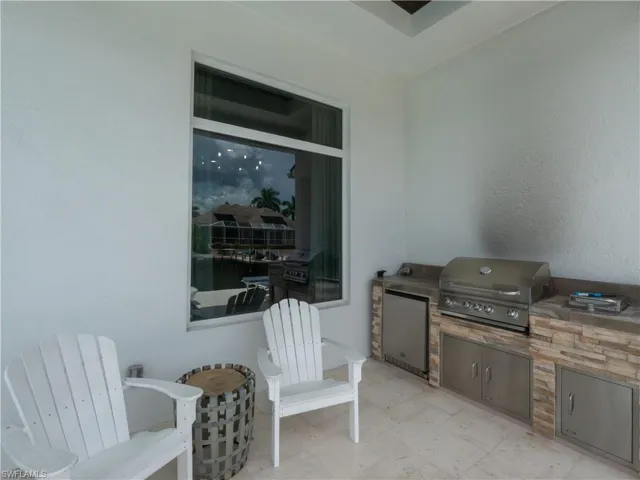 Outdoor kitchen featuring a built-in grill, integrated refrigerator, and stone-clad base