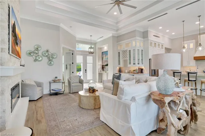 Open-concept living space featuring high tray ceilings with recessed lighting, an integrated ceiling fan, and wood-finish flooring
