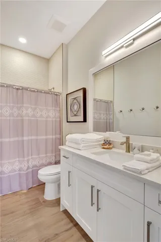 Bathroom featuring a white vanity with brushed nickel hardware, an integrated sink, and a light-toned countertop