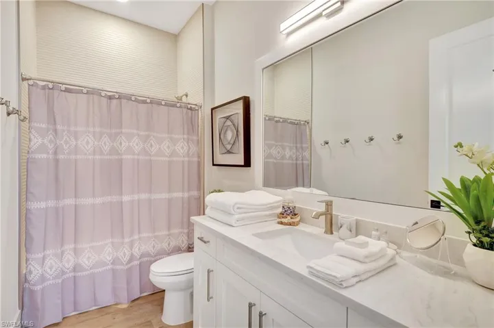 Bathroom with a wide vanity featuring a drop-in sink, gold-finish faucet, and light-toned countertop