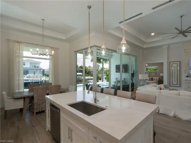 Expansive island kitchen with a stainless steel sink, integrated dishwasher, and pendant lighting