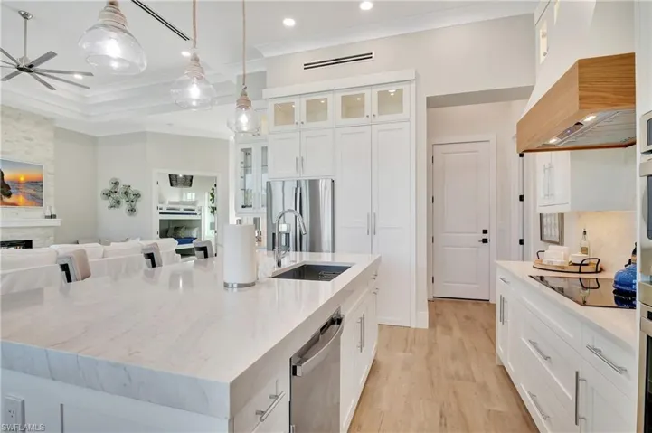 Open concept kitchen featuring an expansive island with an undermount sink, integrated dishwasher, and countertop seating