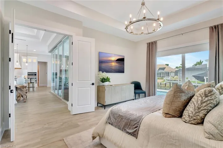 Spacious interior featuring wood-finish flooring, a tray ceiling with a contemporary chandelier, and expansive sliding glass doors