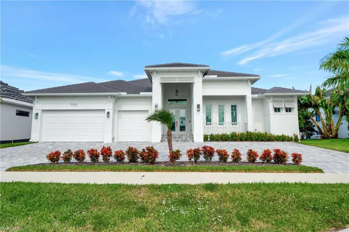 Contemporary white stucco exterior featuring a dark tile roof and a paver driveway