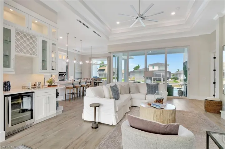 Open-concept living space with wood-finish flooring, a tray ceiling, and a ceiling fan