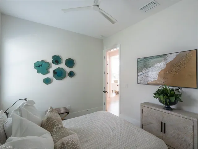 Serene primary bedroom featuring soft neutral finishes, recessed ceiling lighting, and a decorative accent wall displaying sculptural wall art