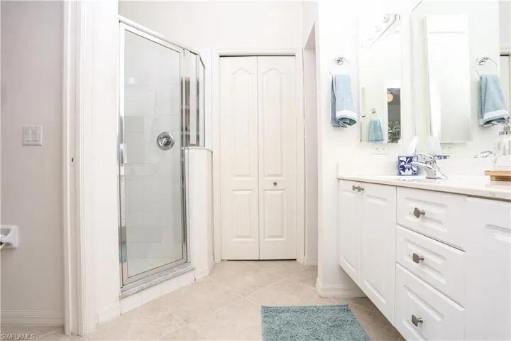 Bathroom featuring vanity, a shower stall, a closet, and tile patterned flooring
