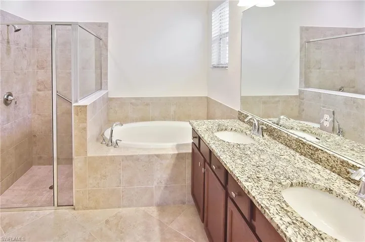 Bathroom featuring independent shower and bath, dual sinks, tile floors, and large vanity