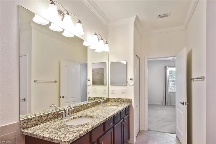 Bathroom with tile floors, crown molding, and double sink vanity