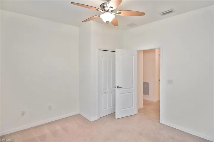 Unfurnished bedroom with ceiling fan, a closet, and light carpet