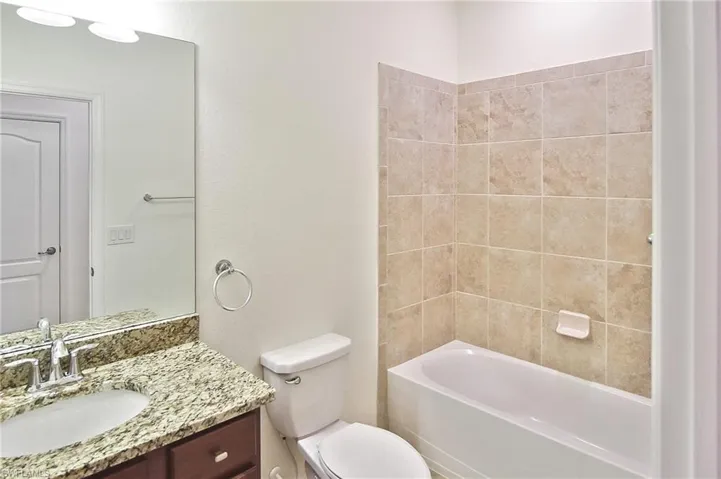 Full bathroom featuring tiled shower / bath, vanity, and toilet
