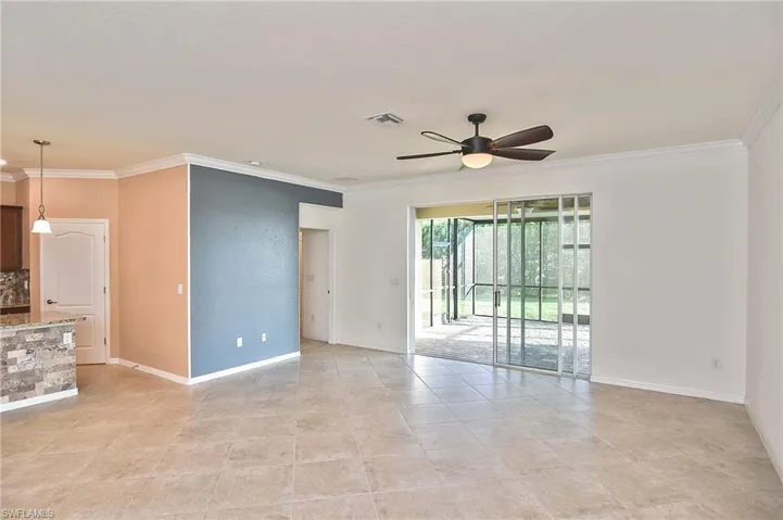 Unfurnished living room featuring ornamental molding, ceiling fan, and light tile floors