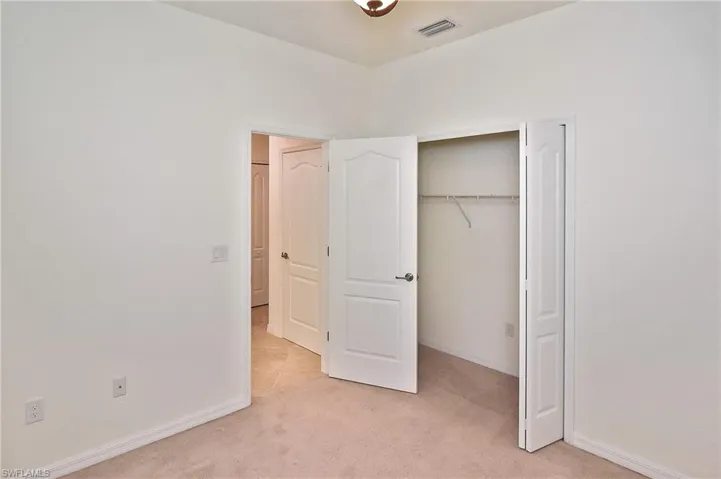 Unfurnished bedroom featuring a closet and light colored carpet