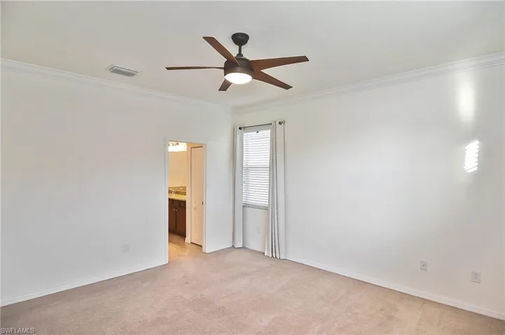 Carpeted spare room featuring ceiling fan and crown molding