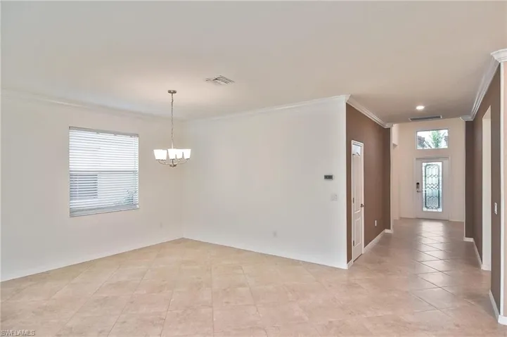Tiled empty room with crown molding and an inviting chandelier