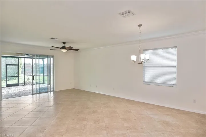 Tiled empty room with ceiling fan with notable chandelier and ornamental molding