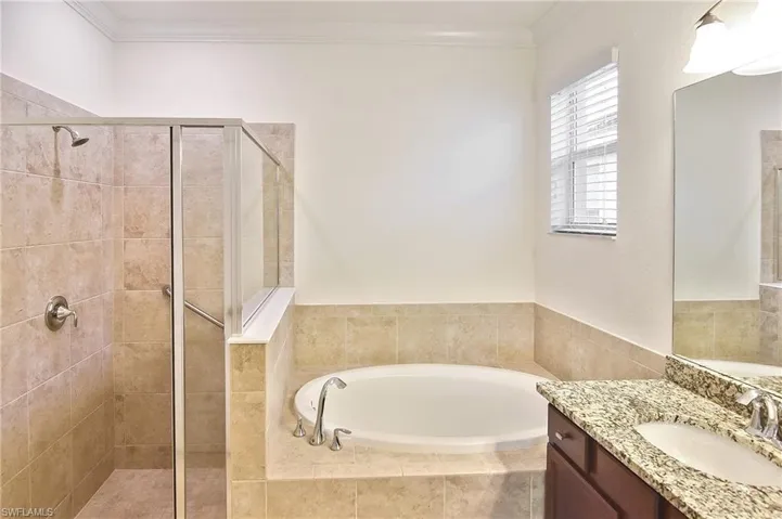 Bathroom with ornamental molding, large vanity, and independent shower and bath
