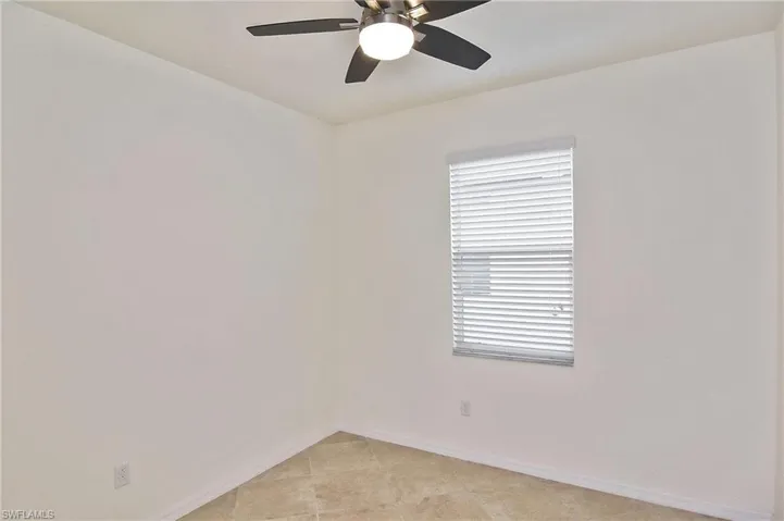 Tiled empty room featuring ceiling fan
