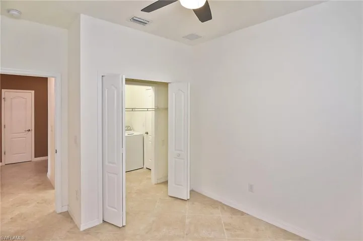 Unfurnished bedroom with separate washer and dryer, a closet, ceiling fan, and light tile floors