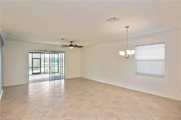 Unfurnished room with ornamental molding, light tile floors, and ceiling fan with notable chandelier