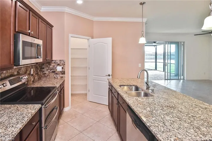 Kitchen featuring hanging light fixtures, appliances with stainless steel finishes, sink, and ceiling fan