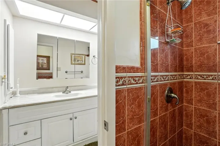 Bathroom with vanity, a shower stall, and a skylight