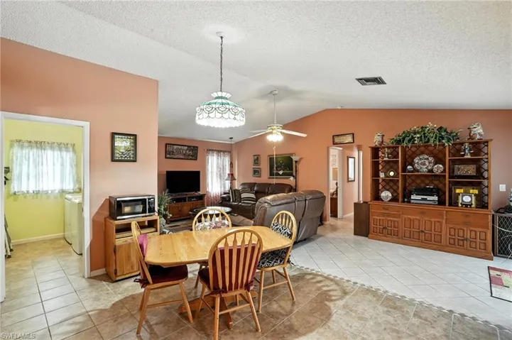 Dining room with vaulted ceiling, light tile patterned floors, a ceiling fan, a textured ceiling, and washer / dryer