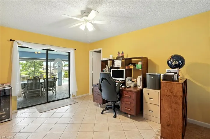 Office area with light tile patterned flooring, wine cooler, a textured ceiling, and a ceiling fan