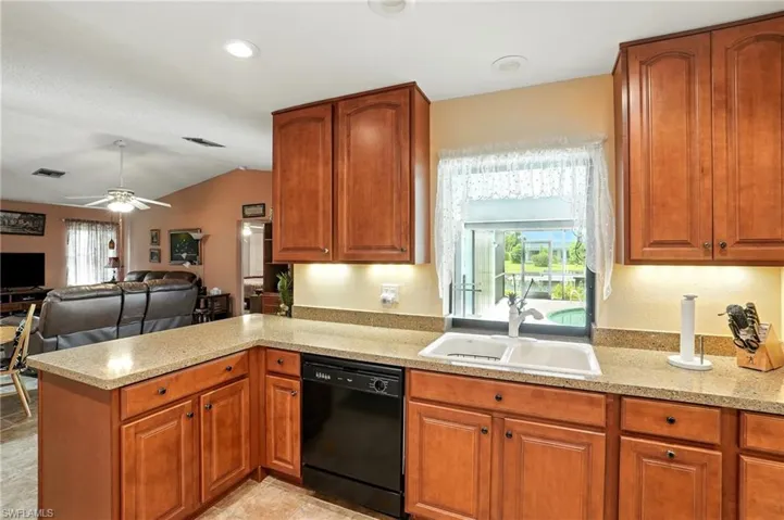 Kitchen featuring a peninsula, dishwasher, open floor plan, brown cabinets, and recessed lighting