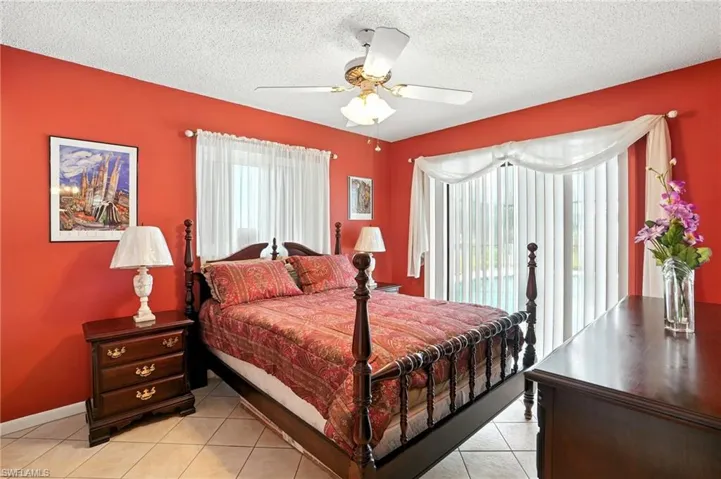 Bedroom with light tile patterned flooring, access to outside, a textured ceiling, and a ceiling fan